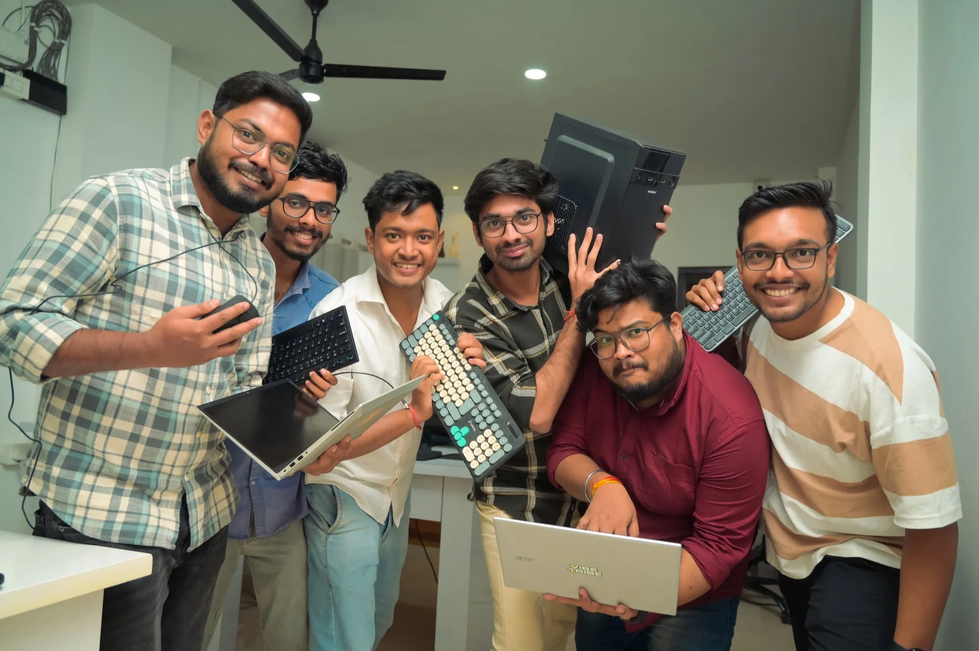 The team crowded together holding laptops, keyboards and a desktop tower.